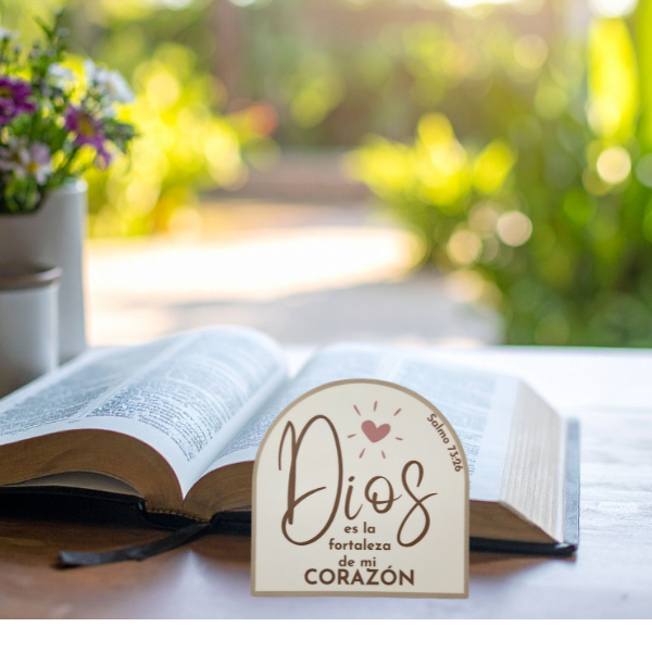 Open book with a decorative sticker reading 'Dios es la fortaleza de mi corazón Salmo 73:26 on a table outdoors.