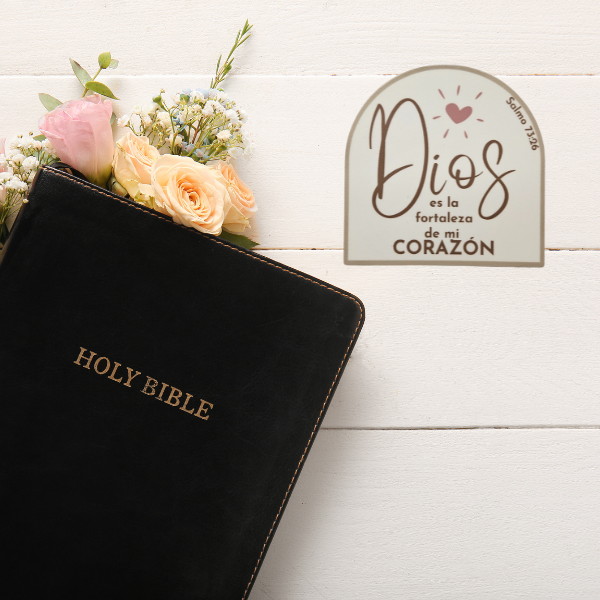Black Holy Bible with flowers and a decorative sticker Dios es la fortaleza de mi corazón Salmo 73:26 on a white wooden surface